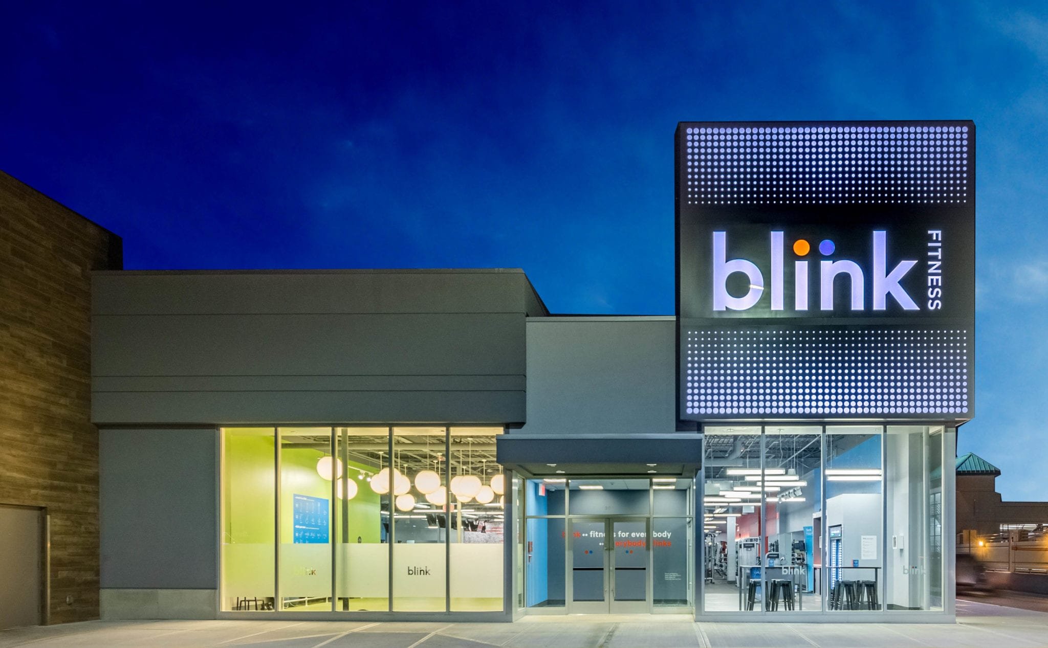 Blink Fitness storefront at dusk with an illuminated dot-matrix sign