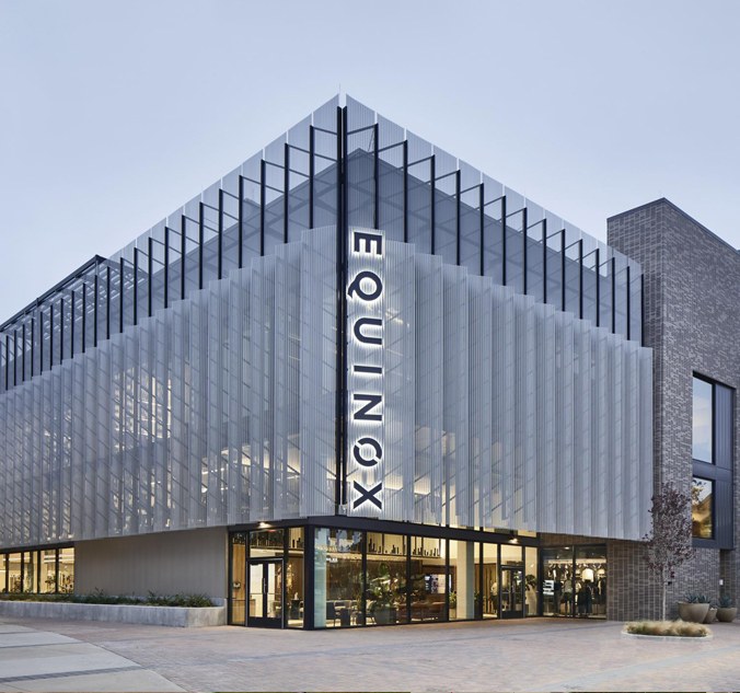 Equinox Plano exterior with vertical EQUINOX signage at dusk