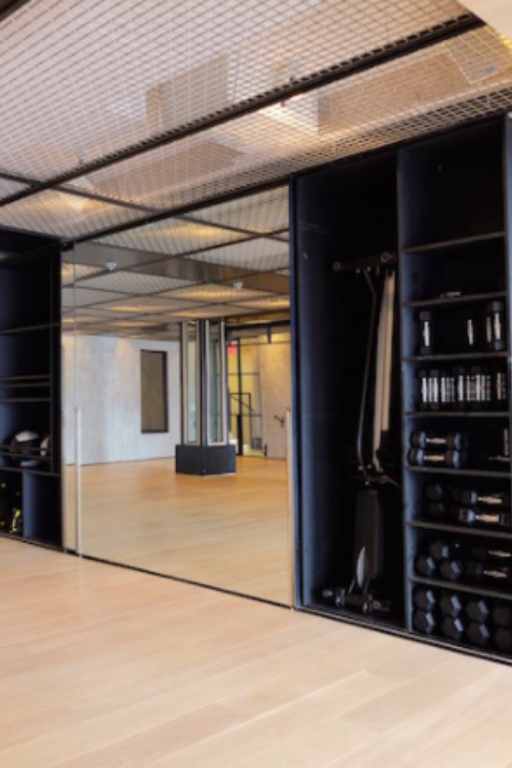 Training floor with a black rig and free weights along a mirrored wall
