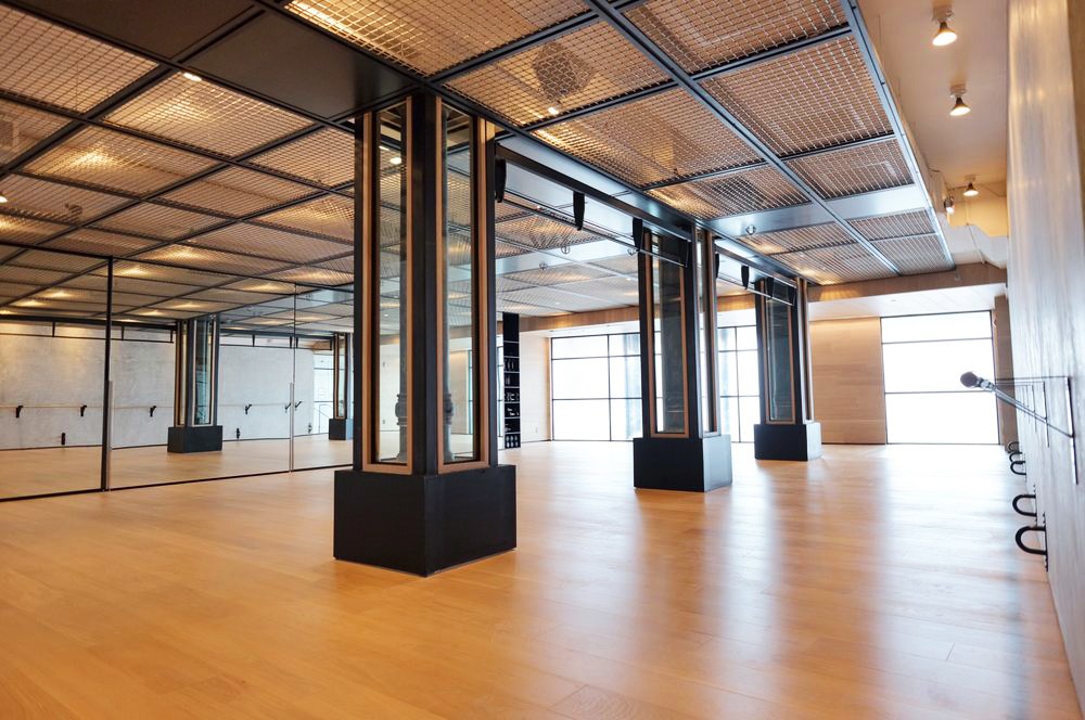 Empty studio with a timber floor, black columns, and a mirrored wall