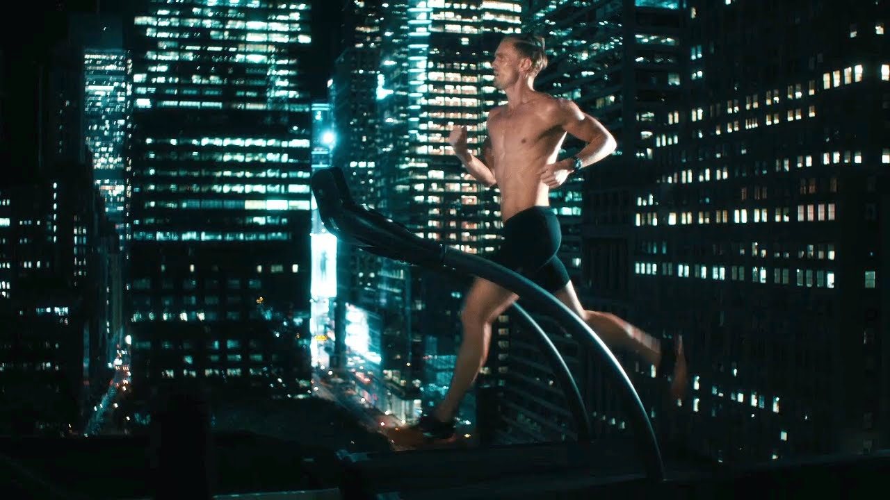 A runner on a treadmill against a night city backdrop