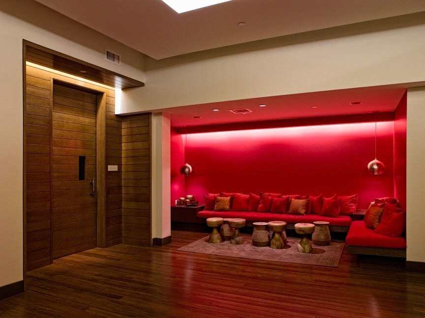 Deep red lounge with a low banquette and carved stools
