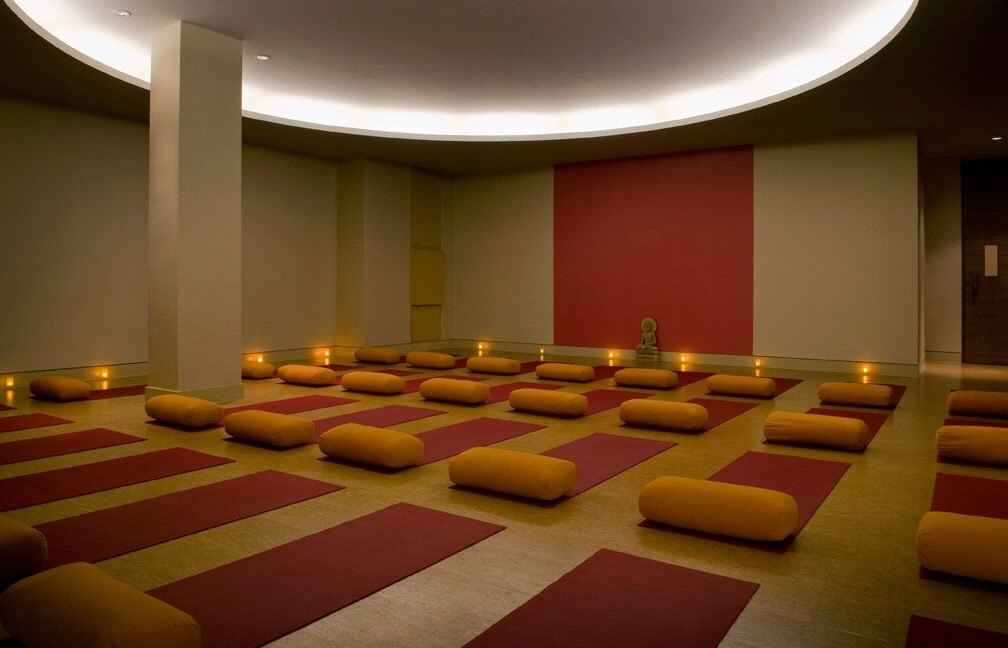 Candlelit meditation room with red mats and saffron bolsters