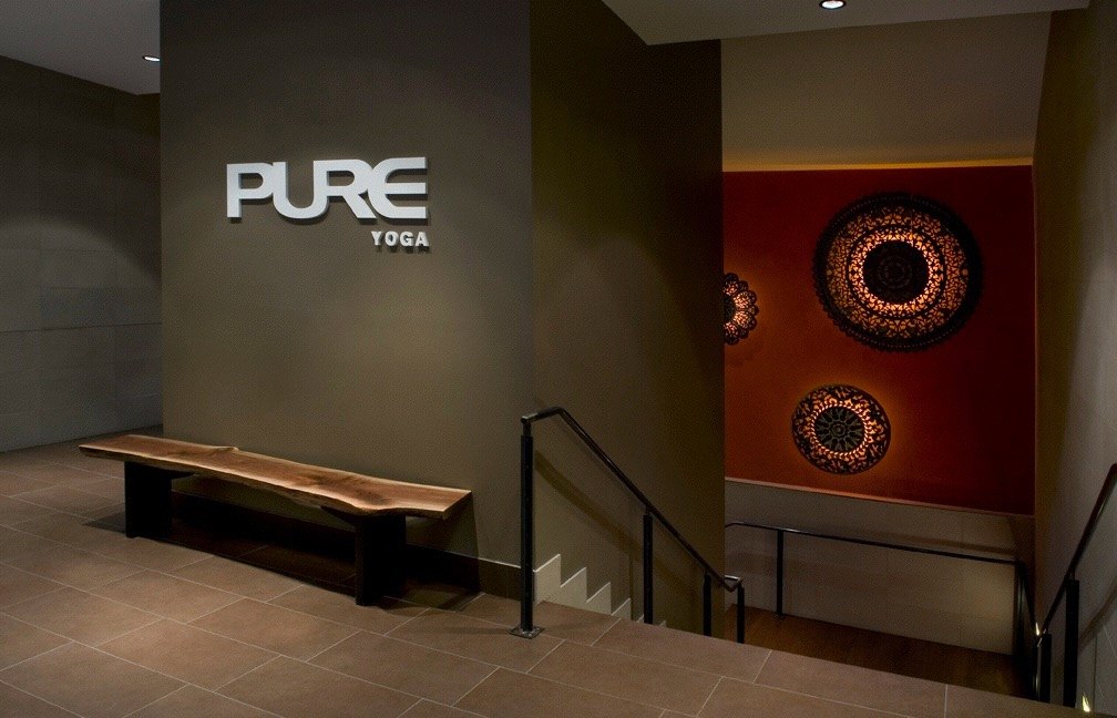 PURE wordmark on a dark wall above a live-edge bench